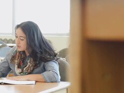 Hispanic adult male and female students studying together at table in college library Stock Footage