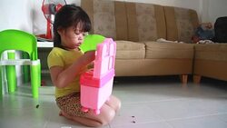 Dolly shot girl is playing dough with toy in her house Stock Footage