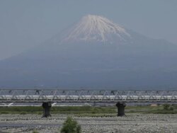 WS View of Bullet train Shinkansen passing on bridge in front of snow capped Mount Fuji / Fujigawa, Shizuoka Prefecture, Japan  Stock Footage
