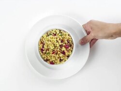 CU Woman hand entering setting down round white plate with bowl of couscous salad / Omaha, Nebraska, United States Stock Footage
