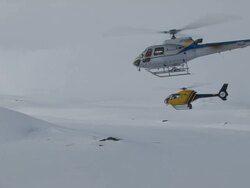 Aerial of two helicopters flying in mountains in winter. Stock Footage
