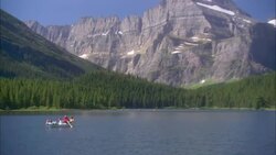 A family rows a rowboat across a mountain lake in Glacier National Park, Montana. Stock Footage