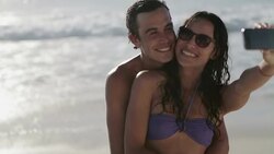 Young couple taking self-portrait with camera phone on beach Stock Footage
