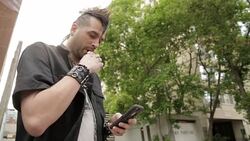 Cool young man with mohawk texting with cell phone and using electronic cigarette Stock Footage