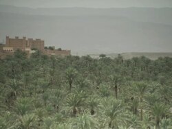 A fort like building sits upon a hill, surrounded by tree and mountains. Stock Footage