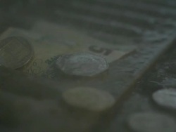 High Speed Rain falling on UK five pound note and coins in drain Stock Footage