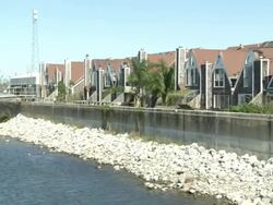Long Shot zoom-in - Townhouses face a levee and a river in New Orleans. / New Orleans, Louisiana, USA Stock Footage