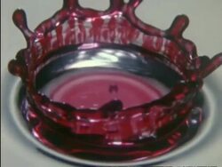 High Speed BCU red drop of liquid splashing into white liquid, colours swirling together, high angle Stock Footage