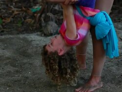 MS TU Little girl hangs upside down using fabric then she turns herself upright as woman and little girls cheer her on / Montezuma, Puntarenas, Costa Rica Stock Footage