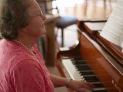 A handheld shot of an elderly woman playing the piano. Stock Footage