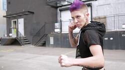 Cool tough young woman posing in fighting stance in urban alley Stock Footage