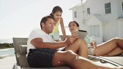 Couple with daughter using digital tablet outside beach house Stock Footage