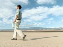 Man walking through desert landscape with bottle of water Stock Footage