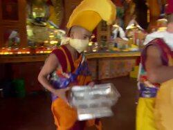 WS ZI POV Young buddhist monks with headgear and scarfs covering their mouths walking  around room preparing for  ritual ceremony  Kopan Monastery  / Kathmandu, Central, Nepal Stock Footage