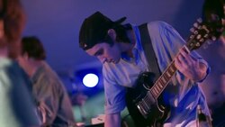 Roadies prepare outdoor stage for concert as young guitarist adjusts levels on his amp Stock Footage