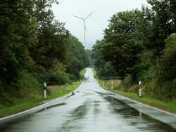 WS Wind turbine turning past wet, country road / Trier, Rhineland-Palatinate, Germany Stock Footage