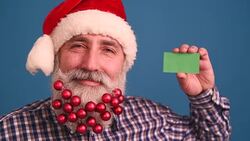 Senior adult man with a beard in elegant hat of Santa Claus on a blue background Stock Footage