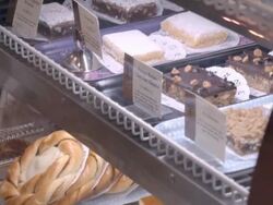 PAN pastries under curve tempered glass in bakery display case and sugar coated cookie lifted by pastry tong / Redlands, California, USA Stock Footage