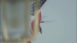 A military helicopter flies above waving American flags. Stock Footage