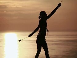 MS Sihouetted female poi dancer dancing in front of fiery sunrise sky and ocean / Montezuma, Costa Rica Stock Footage