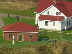 WS ARIEAL DS View of flkag in front of West Quoddy lighthouse / Maine, United States Stock Footage