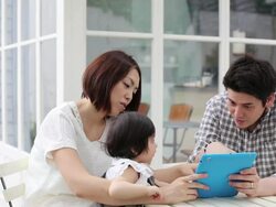 Parents and infant girl using a tablet together on the white terrace Stock Footage