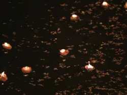 CU Illuminated offerings floating down river Ganges at night / Varanasi, India Stock Footage