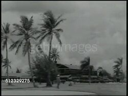 1941: U.S. MARINE BASE IN THE PACIFIC: WS Rocks (jetty) in harbor, ship BG. WS Marine walking across military base. VS Soldiers raising American flag on to pole, saluting, palm trees. WWII, Pacific Front Instructional Video