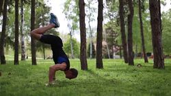 Athlete man exercising and doing hand stand outdoors in a park Stock Footage