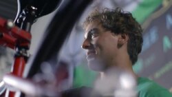 Young mechanic chats with boss while spinning bicycle wheel in bike shop Stock Footage