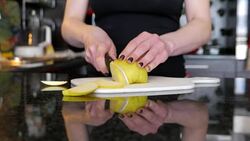 Young woman cutting a green apple in the kitchen Stock Footage