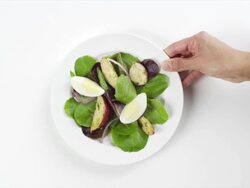 CU Woman hand entering setting down round white plate with spinach, hard boiled eggs, boiled potatoes salad / Omaha, Nebraska, United States Stock Footage