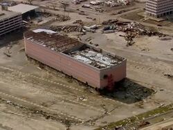 Aerial zoom out damaged roof of Copa Casino surrounded by debris / Mississippi Sound in background / Gulfport, medium shot Stock Footage