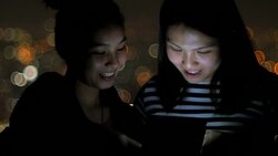 Two young woman playing tablet at night Stock Footage