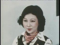 An Asian woman poses for a photographer who takes her picture with an early digital camera and Sony cartridge; the photographer uses a Mavigraph printer to produce the photo, as well as a video screen for viewing. News Clip