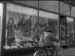 1952: ELKHORN, WISCONSIN: VS Vehicles driving on snow covered streets, various pedestrians, including children, window shopping along street, storefronts, female & grocer carrying grocery bags to car. WI Instructional Video