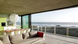 Living room sliding doors open to balcony overlooking ocean Stock Footage