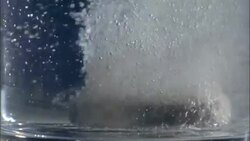 An effervescent tablet drops into a glass of water and bubbles. Stock Footage