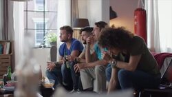 Guys sitting on couch watching tv and clinking bottles Stock Footage