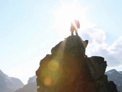 Pan upwards to businessman climbing rock pinnacle Stock Footage