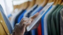 Clothing shop employee checks shirt tags and manages inventory with tablet Stock Footage