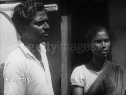 1949: INDIA CASTE SYSTEM: OUTCASTS / UNTOUCHABLES: VS Tagador, husband, father haggling (No SOT) about price of basket making supplies, picking up two bundles of sticks. VS Men sitting outside weaving tall baskets. Indian, arts & crafts, poverty. Instructional Video
