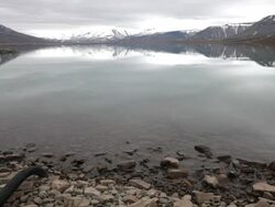 A beautiful house on a a magnificent arctic lake shore with mountains covered by snow in the back, Spitsbergen, Svalbard archipelago Stock Footage