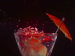 SLOMO CU slice of lemon falling in to cocktail and spilling drink, red lighting, black background Stock Footage