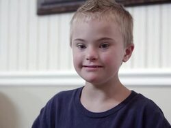 Medium shot of Downs Syndrome boy in a blue shirt Stock Footage