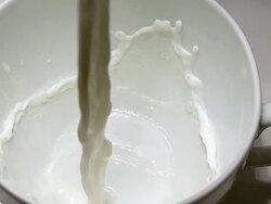 Milk being poured into Cup against white background, slow motion Stock Footage
