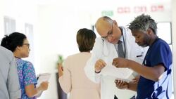 Doctor and surgeon reviewing medical record in hospital corridor Stock Footage
