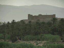 A fort like building sits upon a hill, with Moroccan mountains in the background. Stock Footage