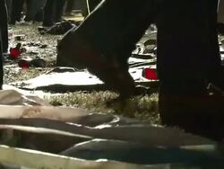 Medium Shot Low Angle - Low angle on people's shoes walking through muddy field with trash, mostly empty plastic beer and water bottles / New Orleans Louisiana Stock Footage
