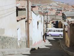 MS Shot of street between houses with vehicles moving / Potosi, Bolivia Stock Footage